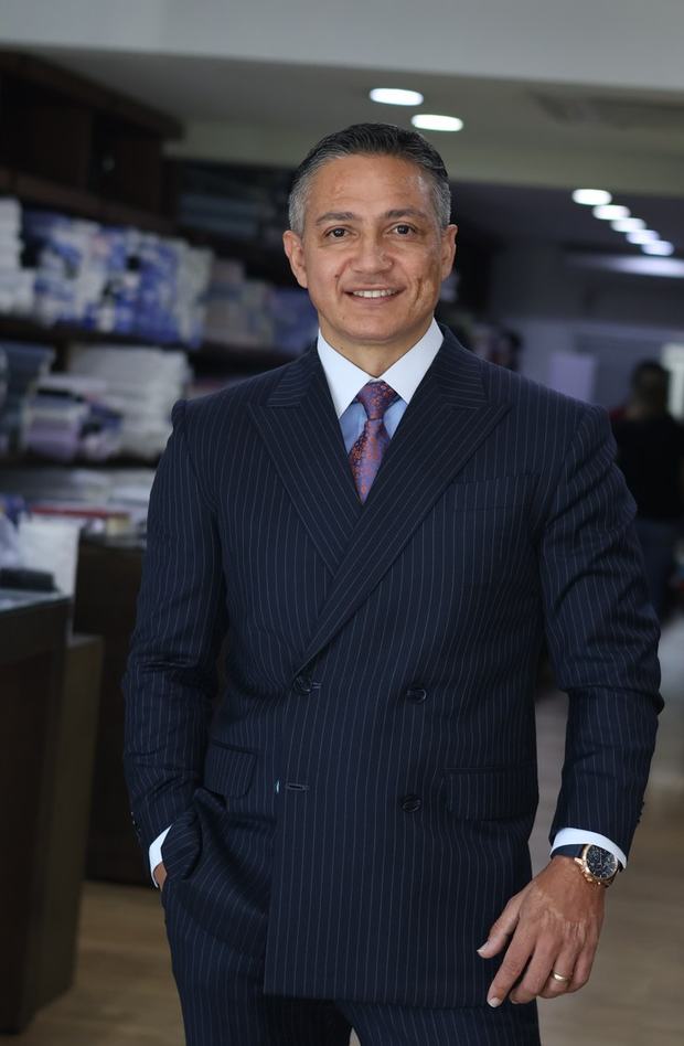 Prof. Dney Santos, de terno, em pé na alfaiataria